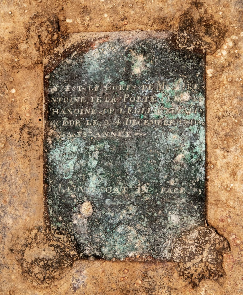 На свинцовом гробу есть бронзовая табличка, идентифицирующая покойного как Антуана де ла Порта, каноника собора Нотр-Дам