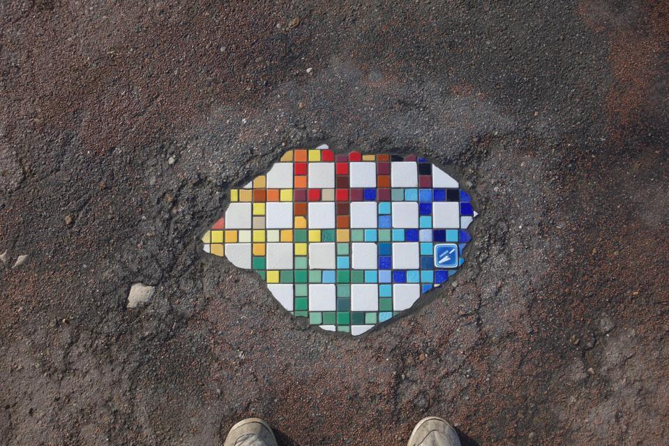 Вуличний художник перетворює міські ями на кольорову мозаїку