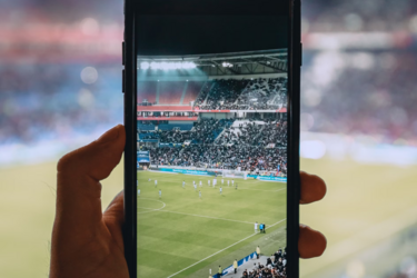 Фото футбольного стадиона, снятого через смартфон с трибуны