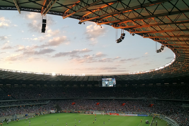 Футбольний матч на великому стадіоні під час заходу сонця