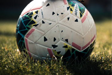 Футбольный мяч на поле под бутсой игрока