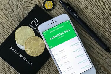 Смартфон с криптокошельком и монеты Bitcoin на столе