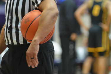 Судья с баскетбольным мячом на площадке во время игры