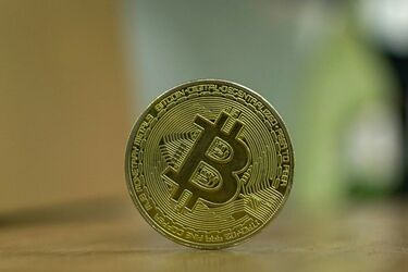 Золота монета з символом біткоїна на дерев'яній поверхні