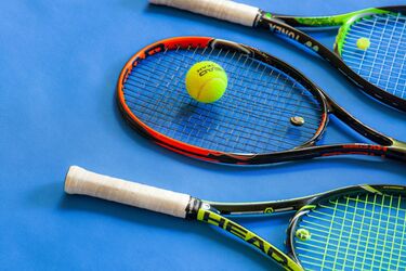 Три теннисные ракетки с мячом на синем корте