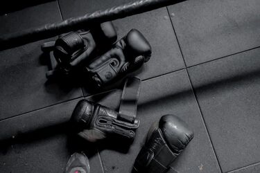 Чёрные боксёрские перчатки на полу тренажёрного зала после интенсивной тренировки