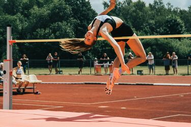 Легкоатлетка выполняет прыжок в высоту на соревнованиях под открытым небом
