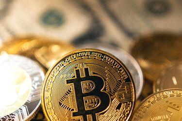 Биткоин-монеты на фоне долларовых купюр, символизирующие рынок криптовалют