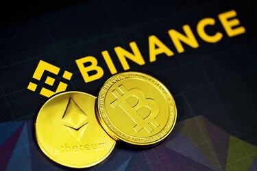 Золотые монеты Bitcoin и Ethereum на фоне логотипа Binance