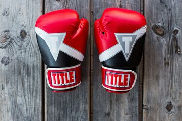 Червоні боксерські перчатки на дерев'яній поверхні