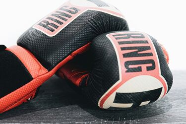 Чорно-червоні боксерські рукавиці з написом 'RING' лежать на рингу