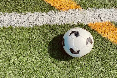 Футбольний м'яч на штучному полі біля білої та жовтої ліній розмітки