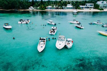 Чистая бирюзовая вода с пришвартованными яхтами и отдыхающими людьми у побережья Каймановых островов