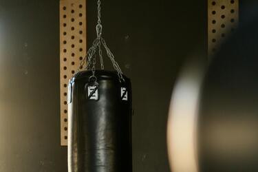 Чорна боксерська груша, підвішена на ланцюгах у тренувальному залі