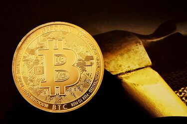 Золотая монета Bitcoin на фоне слитка золота