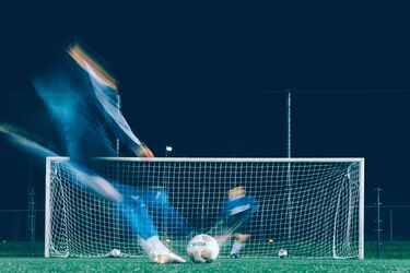 Футболіст пробиває пенальті на тренуванні вночі