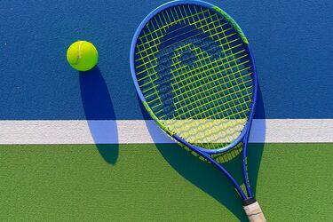 Теннисный мяч и ракетка на корте под солнечным светом