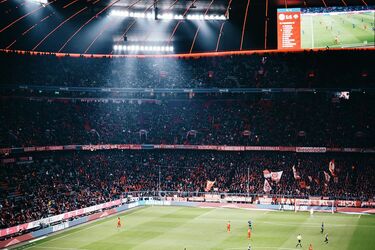 Футбольний матч на стадіоні з яскравою підсвіткою та великою кількістю вболівальників