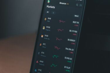 Смартфон із відкритим додатком Binance та графіками криптовалют