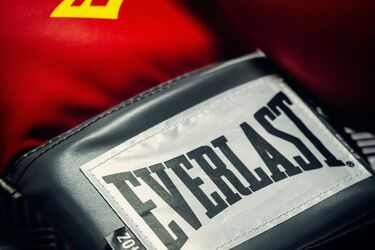 Красные боксерские перчатки бренда Everlast на черном рифленом покрытии