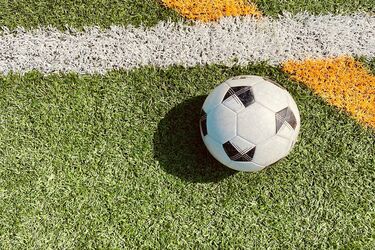 М’яч на футбольному полі біля перетину білої та жовтої ліній